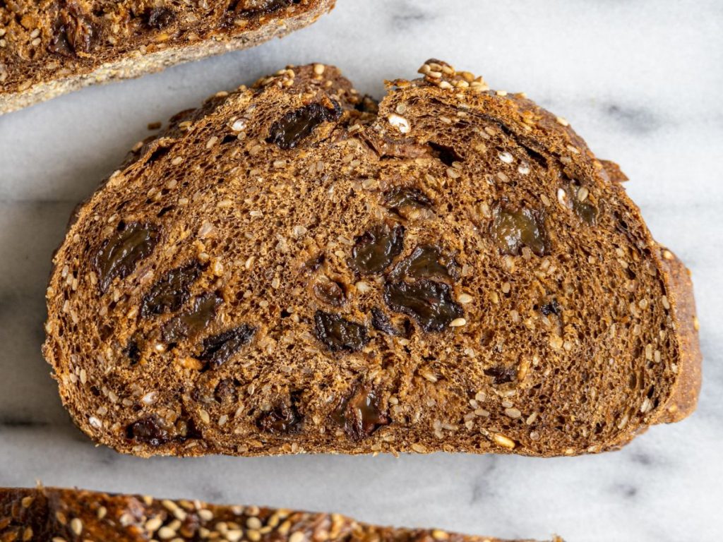 a slice of pumpernickel bread with brown raisins in the middle with a crust around the slice of raisin bread